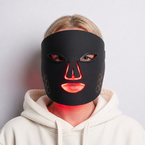 Woman wearing Lumé red light therapy face mask with red light glow visible through mask